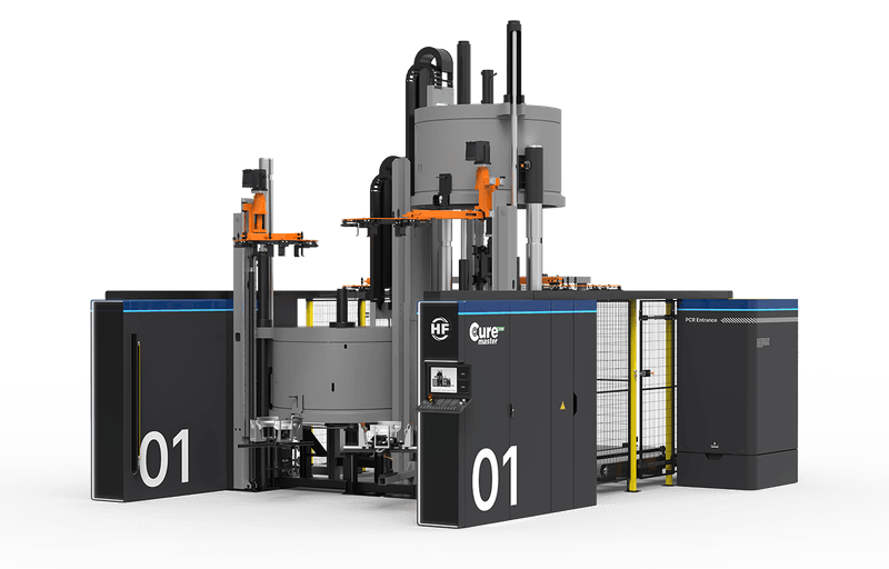 Large electric tyre curing press with central round modules, protective cladding and vertical superstructures.