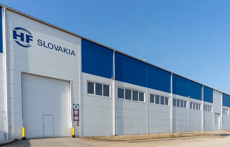 Exterior view of the blue and white factory building in Dubnica nad Váhom, Slovakia, belonging to the HF GROUP