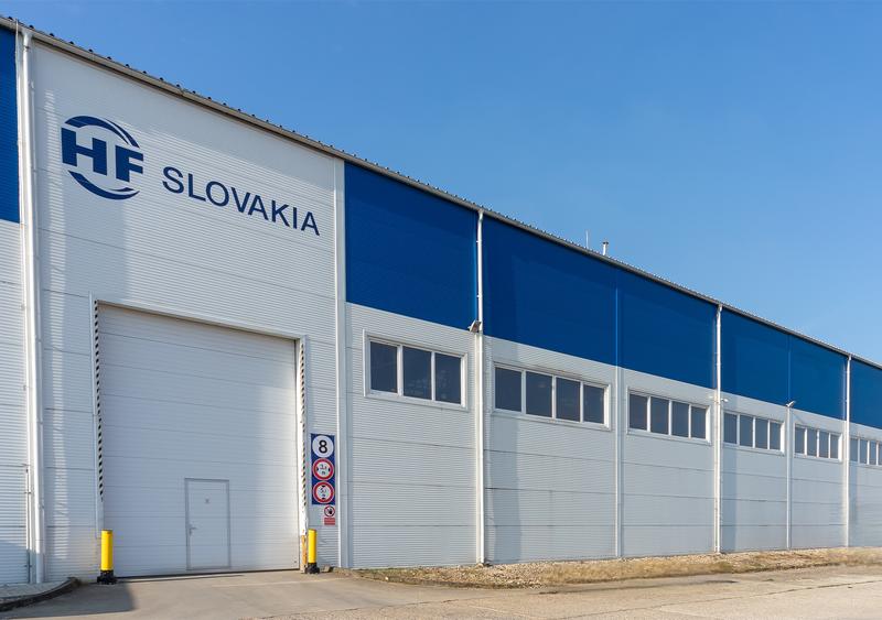 alt=”Exterior view of a production hall labelled SLOVAKIA.”