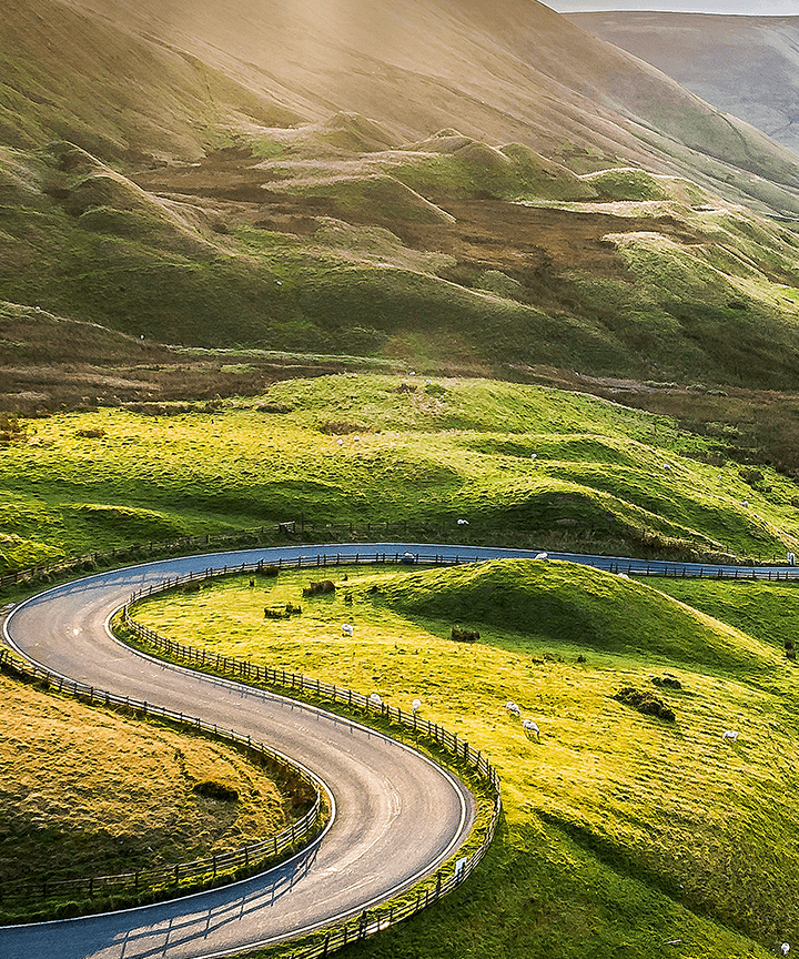 Winding road snakes through a green hilly landscape.