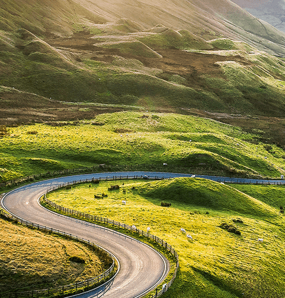 Winding road snakes through a green hilly landscape.