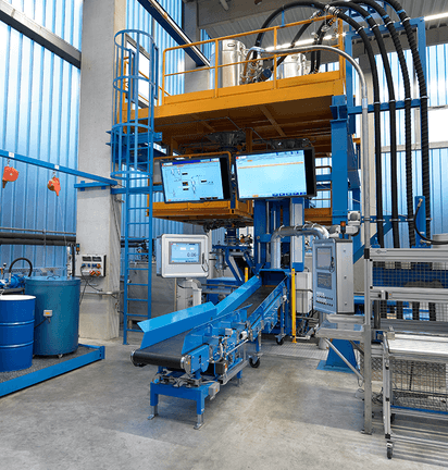 Industrial station with conveyor belt, control screens, barrels, and elevated equipment platform.